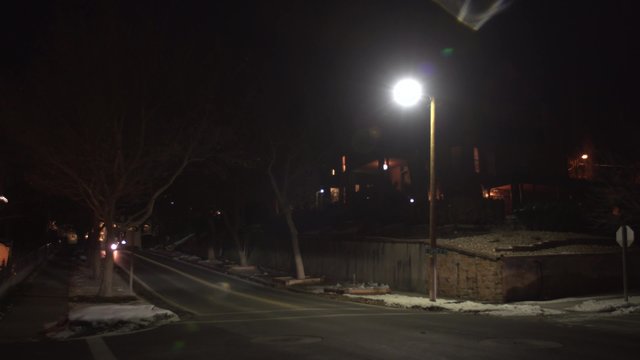 A streetlight shines on a lonely street corner on a winter night.