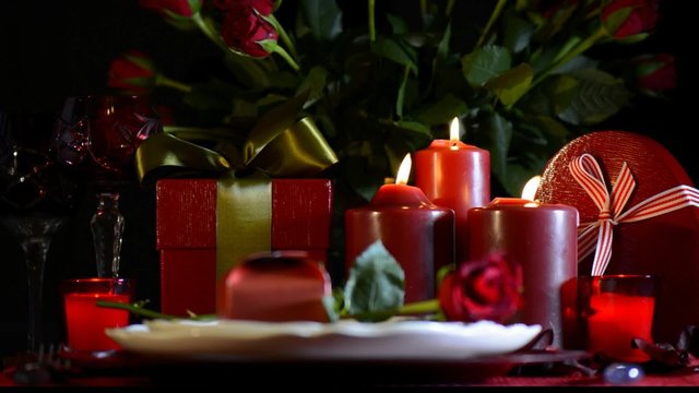 Romantic Valentine table setting with candle light and roses with focus on candles.