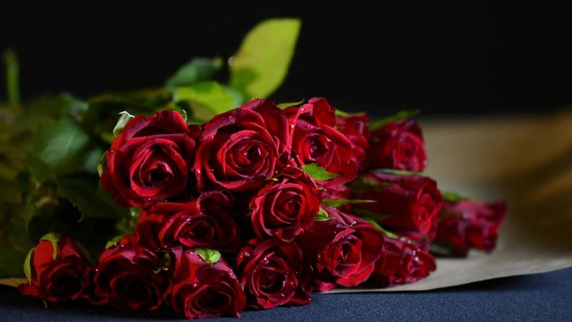 Wrapping Valentine Red Roses in natural brown paper, closeup