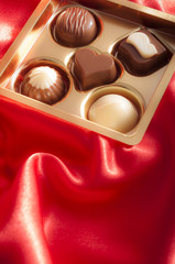 Golden box of chocolates on a red silk background for Valentine's day