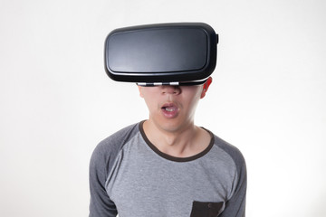 Asian man wearing VR goggle and immersing himself in VR multimedia in white isolated.