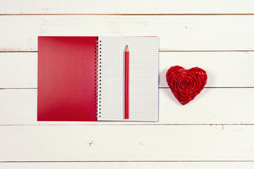 Notebook and heart on a white rustic background. Valentine's Day. Top view
