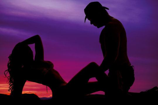 Silhouette of a woman in a bikini lay back cowboy over her
