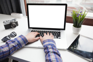 Man's hands using laptop and a table pc with blank screen on des