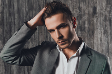 Obraz premium Attractive rigid man in business suit on the grey background