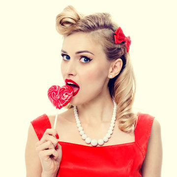 young woman eating colourful lollipop, dressed in pin-up style