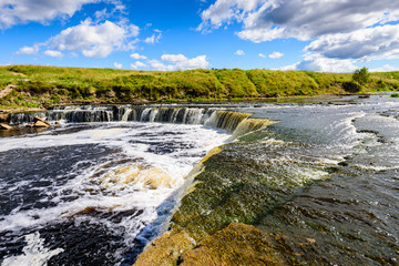 Fototapeta na wymiar A picturesque waterfall on the river Sablinka, Tosnensky district, Leningrad region, Russia.