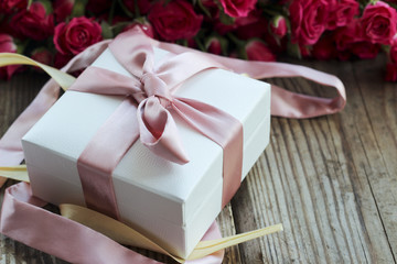 Holiday background with pink roses and gift box