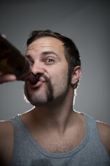 Junger Mann mit Bart trinkt Alkohol