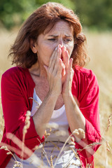 outdoors illness - beautiful 50s woman sneezing for rhinitis,allergies or hay fever reaction,summer...