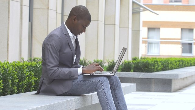 happy African American entrepreneur displaying computer laptop on. outdoors