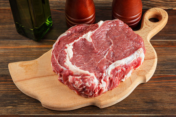 Raw rib-eye steak on a cutting board