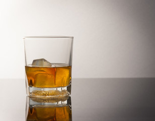 whiskey glass with ice cubes and reflection drink alcohol on gre