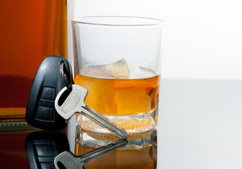 Glass of whiskey and car keys on gradient background