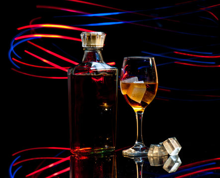 bottle and wineglass of whiskey with ice on dark background,curv