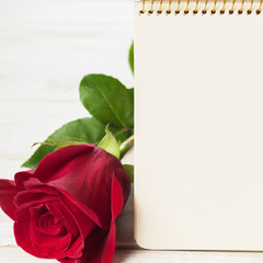 Blank card with red rose on a wooden background