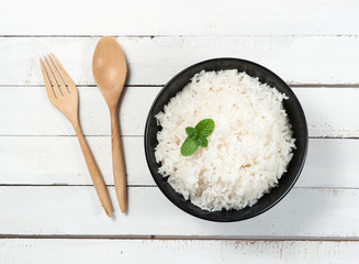 bowl full of rice and spoon on wood background