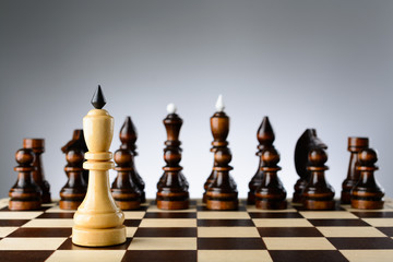 The white king on a background of black chess pieces