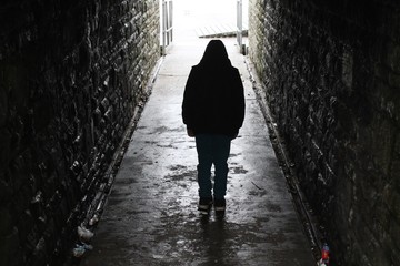 Hooded boy silhouetted in an underground tunnel