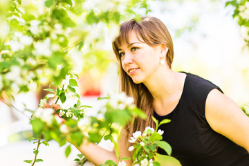 Beautiful young woman over white blossom tree, outdoors portrait