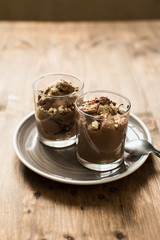Vegan chocolate mousse (pudding) from tofu in a glass bowl with a silver spoon. Rustic tablecloth in the background, close up. 