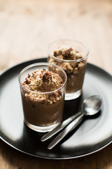 Vegan chocolate mousse (pudding) in a glass bowl with a silver spoon. Rustic tablecloth in the background, close up. 