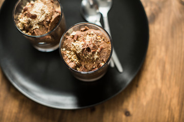Vegan chocolate mousse (pudding) in a glass bowl with a silver spoon. Rustic tablecloth in the background, close up. 