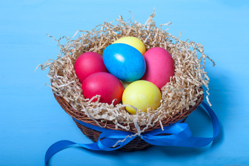 Fototapeta na wymiar Easter eggs in a nest on blue background