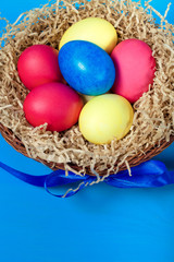 Fototapeta premium Easter eggs in a nest on blue background. Toned