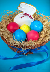 Fototapeta na wymiar Easter eggs in a nest and gingerbread on a blue background. Tone