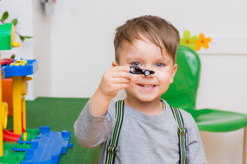 kleiner junge spielt mit autos im kindergarten