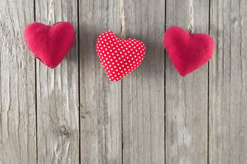 Three red hearts on a wooden background