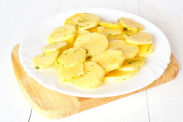 Naklejka na ściany i meble Diced potatoes with spices on a white plate on a board