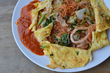 stir fried sukiyaki with seafood wrapped in egg and dressing sauce on dish