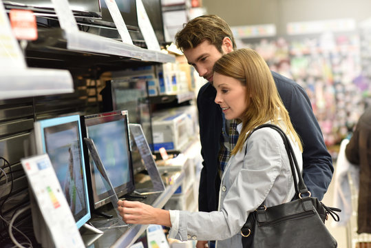 Couple in department store choosing television set