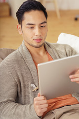 entspannter junger mann liest zuhause am tablet