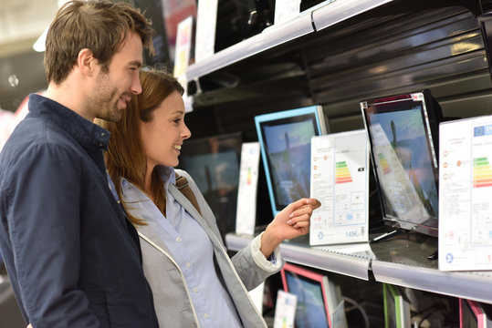 Couple in department store choosing television set