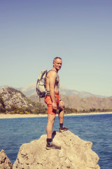 Fototapeta na wymiar Hiker man stands on a rock by the sea