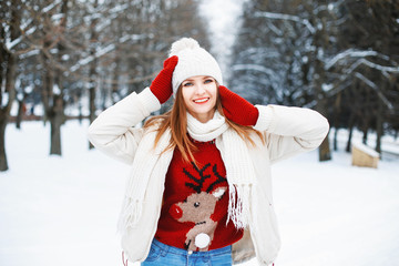 Girl in stylish winter clothes resting in a park on a background of trees