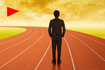 businessman standing on running track and looking to goal