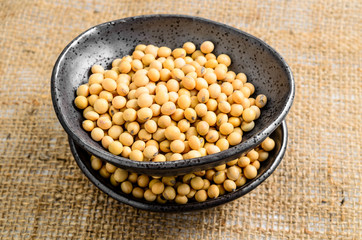 soybeans in ceramic bowl on sackcloth background..