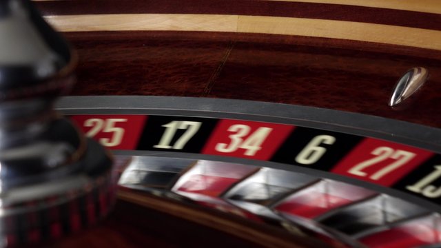 Roulette wheel running and stops with white ball on red