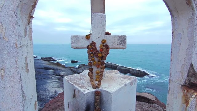 White cross with flowers on the hill at the ocean coast