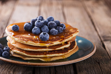 Pancake folded stack of with liquid honey and fresh blueberries on wooden background.selective focus.