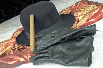 Fototapeta premium Black hat on a brown scarf with black leather gloves and a cigar