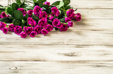 Pink roses flowers on wooden planks background wth copyspace.