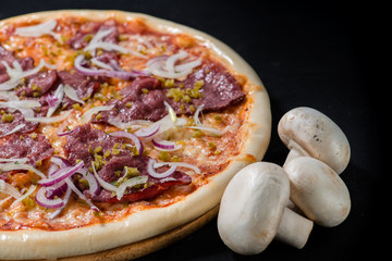 closeup Tasty pizza with tomatoes, cheese, basil and ham on a bl