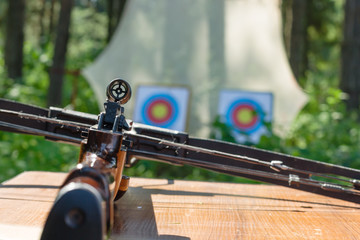 Crossbow lying on a table with targets at backgroung