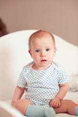 Fototapeta premium Cute baby girl sitting in bed in room. Looking at camera. Childhood. Waking up.