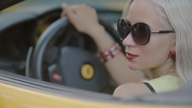 Blonde in sits behind the wheel of cabriolet